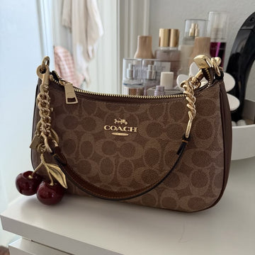 Coach Teri Shoulder Bag in Signature Canvas (brown and tan), decorated with a gold-tone cherry keychain