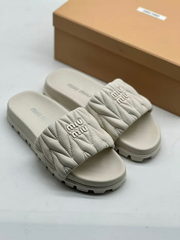 Miu Miu Matelassé Nappa Leather Slides in a cream or beige colorway