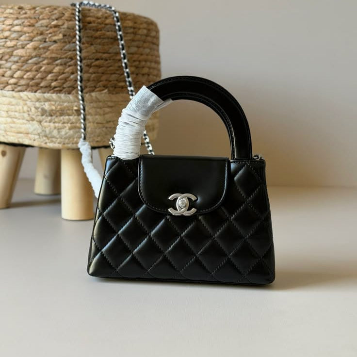 Chanel Kelly Shopping Bag (often called the Chanel Nano or Mini Kelly Shopper) in black quilted leather with a silver-tone CC turn-lock closure.