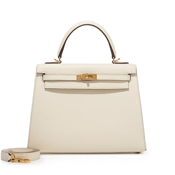 Hermès Kelly Sellier in a neutral shade like Craie or Nata with gold-tone hardware, accented with a tied twilly scarf.